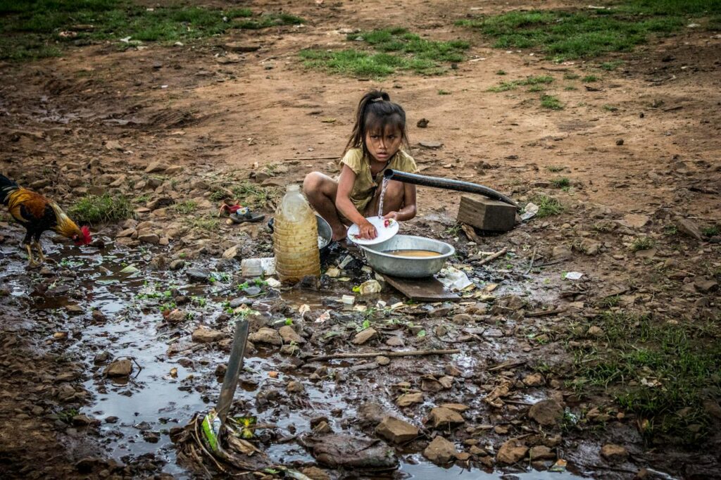 貧困地域で汚れた水で食器を洗う少女の姿